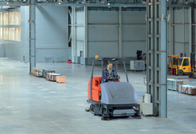 Gebäudereiniger beim maschinellen reinigen einer Industriehalle