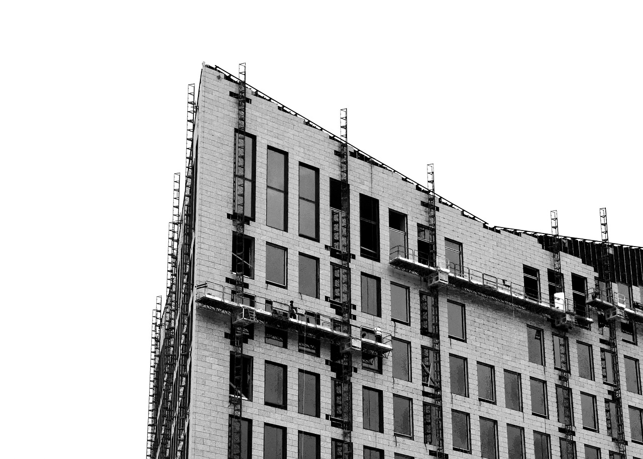 Gebäude mit hohen Fenstern und Gebäudereinigern, die an der Außenfassade in Gondeln stehen und das Gebäude reinigen.